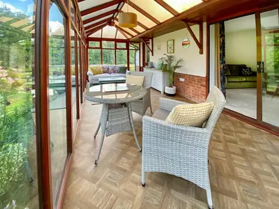 a screened in porch with a table and chairs at Rose Cottage in Blakemere
