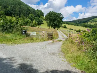 a dirt road in a field with a fence at Llety'r Saer in Pen-y-bont-fawr