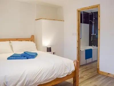a bedroom with a bed and a bathroom with a tub at Llety'r Saer in Pen-y-bont-fawr