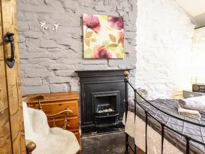 a bedroom with a stone wall with a fireplace at Cartrefle in Bala