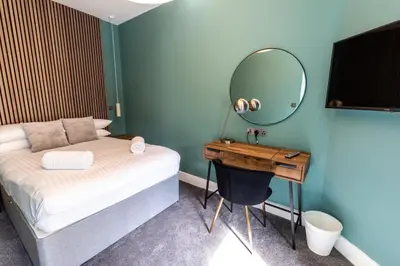 a bedroom with a bed and a desk with a mirror at Ty Belgrave in Aberystwyth