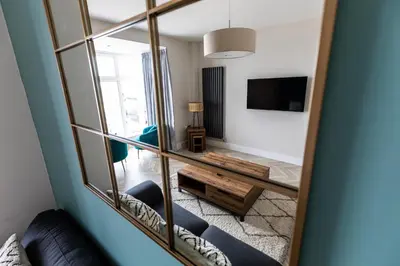 a mirror reflecting a living room with a couch and a table at Ty Belgrave in Aberystwyth