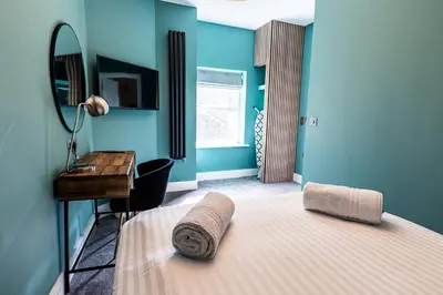 a bedroom with blue walls and a bed with a desk at Ty Belgrave - Apartment 2 in Aberystwyth