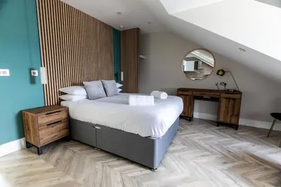 a bedroom with a large bed and a mirror at Ty Belgrave - Apartment 4 in Aberystwyth