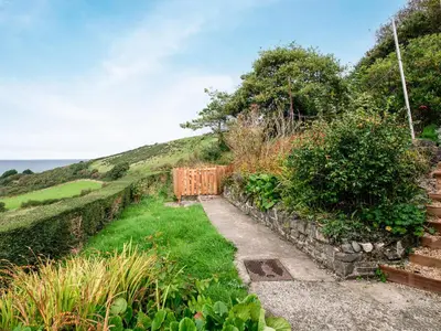 a garden with a wooden gate on the side of a hill at Frondeg in Aberaeron