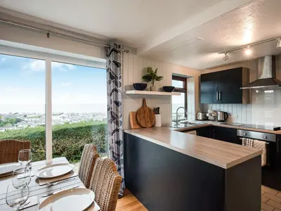 a kitchen with a large window and a table with chairs at Frondeg in Aberaeron