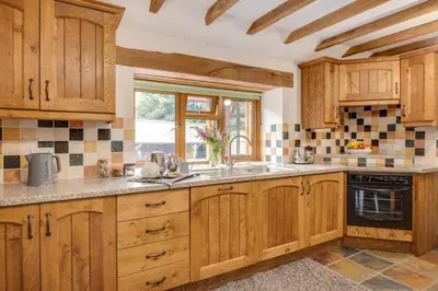 a kitchen with wooden cabinets and a sink and a window at 2 Bed in Dinas Mawddwy oc-bow268 in Machynlleth
