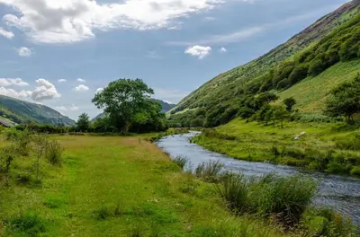 a river in a field with mountains in the background at 3 Bed in Tywyn oc-bow248 in Abergynolwyn