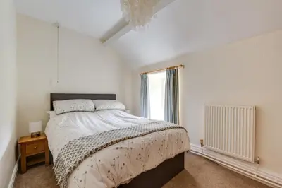 a white bedroom with a large bed and a window at 3 Bed in Tywyn oc-bow248 in Abergynolwyn