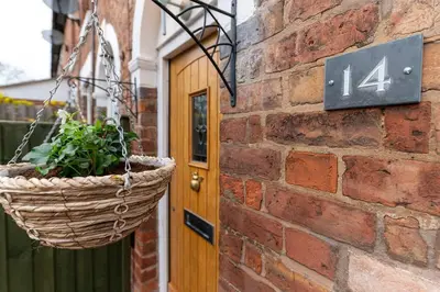 a basket hanging on a brick wall with a door at Besford Square, Shrewsbury Town in Shrewsbury