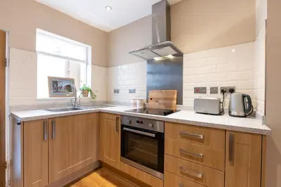 a kitchen with wooden cabinets and a sink at Besford Square, Shrewsbury Town in Shrewsbury