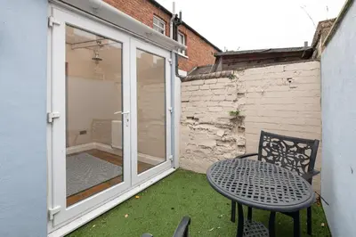 a patio with a table and a chair and a window at Besford Square, Shrewsbury Town in Shrewsbury