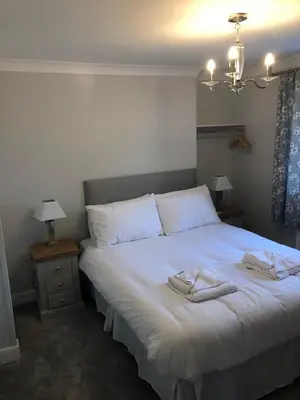 a bedroom with a white bed with two towels on it at Pengarreg Fawr in Aberystwyth