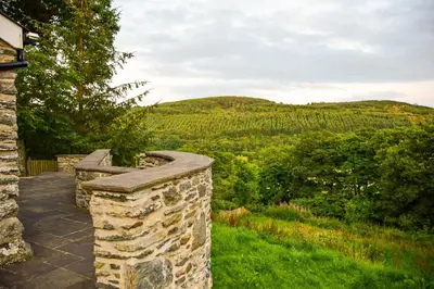 a stone wall with a view of a mountain at Stunning Barn Conversion with HOT TUB and ALPACAS - Ty Cerrig Barn in Corwen