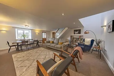 a living room with a couch and a table at Stunning Barn Conversion with HOT TUB and ALPACAS - Ty Cerrig Barn in Corwen