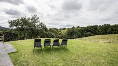 two chairs sitting on top of a grass field at Romantic Couples' Getaway - at Ty Cerrig Barn with luxury hot tub in Corwen
