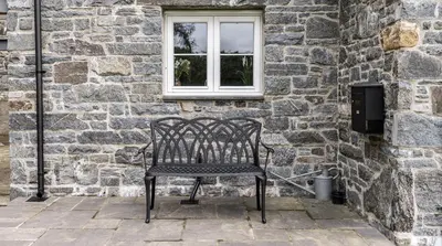 a black bench sitting in front of a stone building at Romantic Couples' Getaway - at Ty Cerrig Barn with luxury hot tub in Corwen