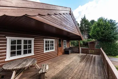 a wooden deck with a bench next to a house at 3 Bedroom Log Cabin in Snowdonia nr MTB trails in Tanygrisiau