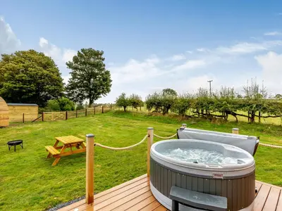 a hot tub on a deck with a picnic table at Elm-Uk36259 in Llanfair Caereinion