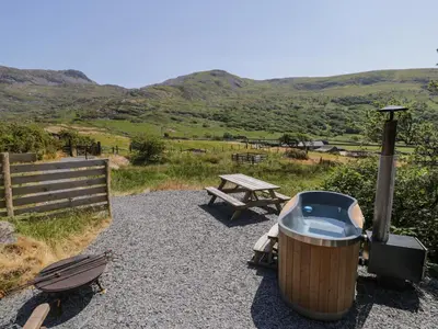 a grill and a picnic table with a table and hills at Llethr - Shepherds Hut in Llanbedr