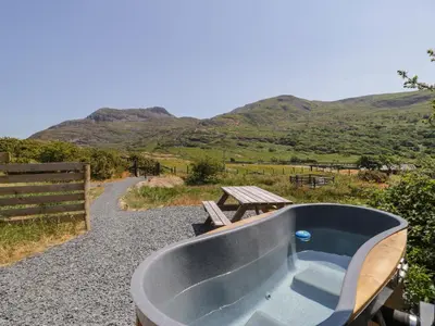 a bath tub sitting on a gravel road with a picnic table at Llethr - Shepherds Hut in Llanbedr