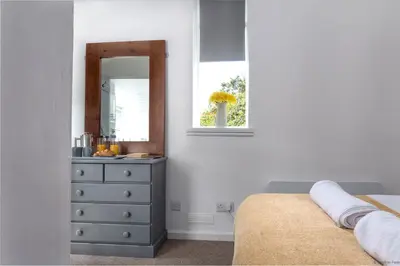 a bedroom with a dresser and a mirror at Cowshed Cottage with Log Burner & Shared Dog Field in Bryn-crug