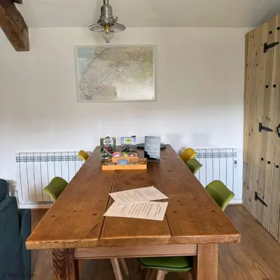 a wooden table in a room with green chairs at Cowshed Cottage with Log Burner & Shared Dog Field in Bryn-crug