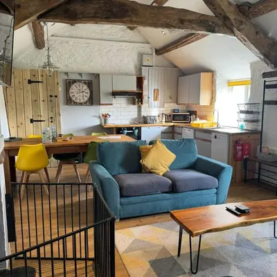 a living room with a blue couch and a kitchen at Cowshed Cottage with Log Burner & Shared Dog Field in Bryn-crug