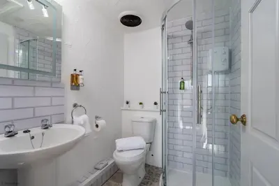a bathroom with a toilet and a sink and a shower at Cozy Log Burner Cottage & On-Site Dog Field in Bryn-crug