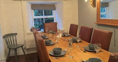 a long wooden table with chairs and wine glasses at Farmhouse with Log Fire & On-Site Dog Field in Bryn-crug
