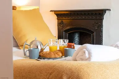 a bed with a tray of croissants and orange juice at Farmhouse with Log Fire & On-Site Dog Field in Bryn-crug