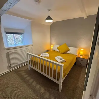 a bedroom with a bed with two towels on it at Farmhouse with Log Fire & On-Site Dog Field in Bryn-crug