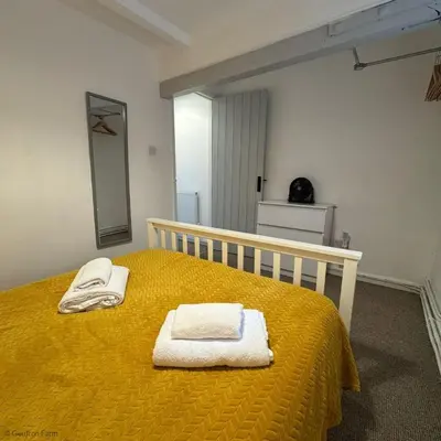 a bedroom with a yellow bed with towels on it at Farmhouse with Log Fire & On-Site Dog Field in Bryn-crug
