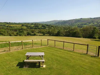 a picnic table sitting in the middle of a field at Ty Barcud in Lampeter