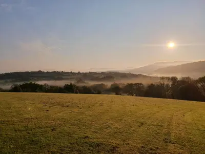 a field with the sun rising over a misty field at Ty Barcud in Lampeter