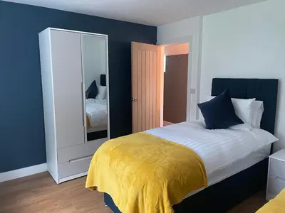 a bedroom with a bed with a yellow blanket and a mirror at Pennant Uchaf in Llanbrynmair