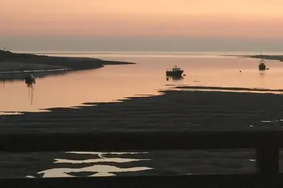 a boat in a body of water at sunset at Hendre Fechan Cottage, Nr Barmouth, Pets welcome, beautiful views. in Llanddwywe