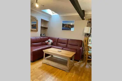 a living room with a brown leather couch and a table at Hendre Fechan Cottage, Nr Barmouth, Pets welcome, beautiful views. in Llanddwywe