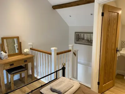 a room with a staircase with a mirror and a table at The Nook at Pentregaer Ucha, with tennis court & lake. in Oswestry