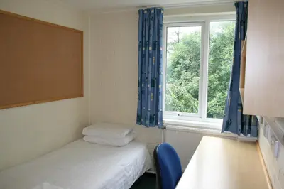 a small room with two beds and a window at Aberystwyth University Bunkhouse in Aberystwyth