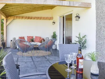 a patio with chairs and a table with wine glasses at Afonig Loyw in Dyffryn