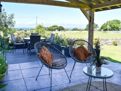 three chairs and tables on a patio with a field at Afonig Loyw in Dyffryn