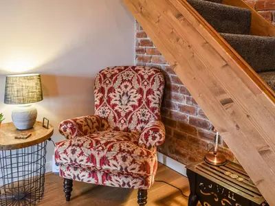 a living room with a chair and a staircase at Afonig Loyw in Dyffryn