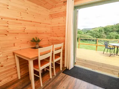 a wooden room with a table and chairs and a large window at Hwyl in Llandrindod Wells