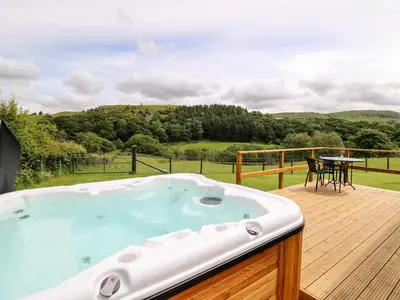 a hot tub on a deck with a table and chairs at Hwyl in Llandrindod Wells