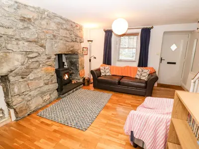 a living room with a couch and a stone fireplace at Gerlan in Harlech