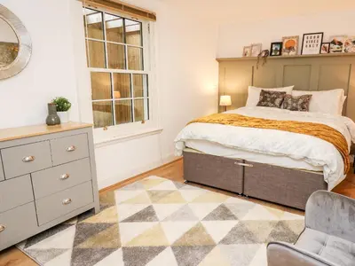 a bedroom with a bed and a dresser and a chair at Bridgend Cottages in Llandrindod Wells