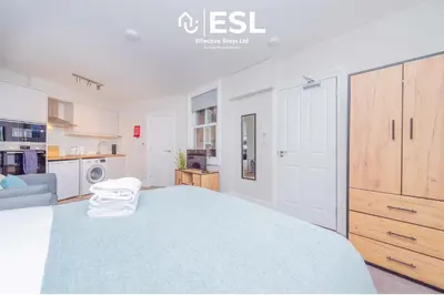 a bedroom with a large bed and a kitchen at Studio 2, Second Floor Town Centre Apartment in Shrewsbury