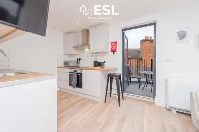 a kitchen with white cabinets and a table and chairs at Studio 3, Top Floor Town Centre Apartment in Shrewsbury