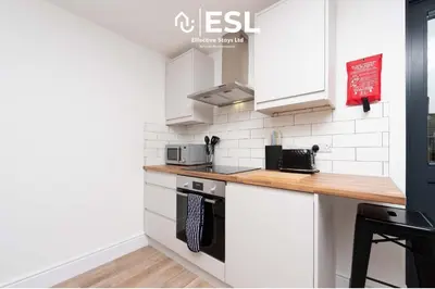 a kitchen with white cabinets and a wooden counter top at Studio 3, Top Floor Town Centre Apartment in Shrewsbury